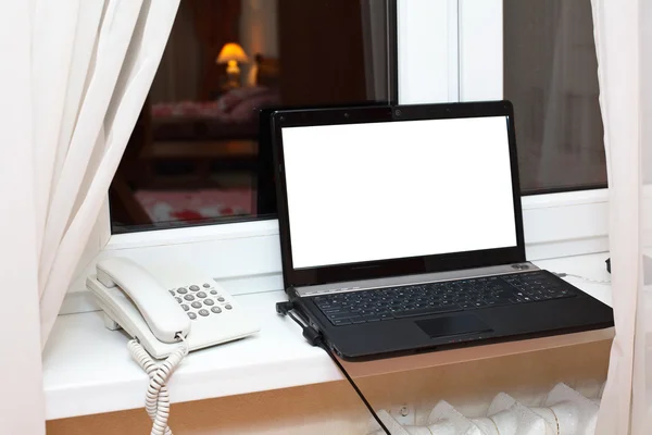 Portátil abierto y teléfono blanco en el alféizar de la ventana — Foto de Stock