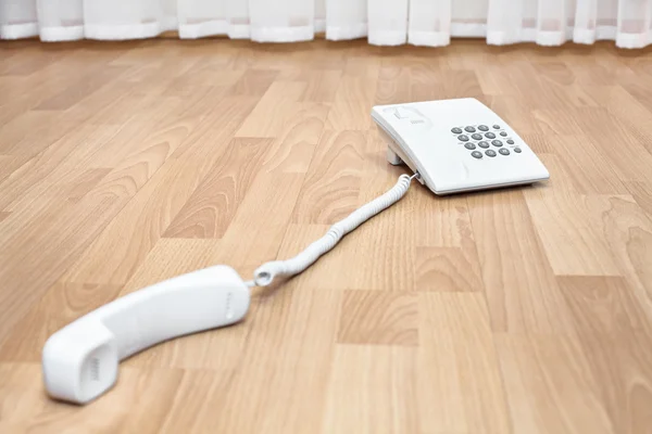White telephone on the parquet floor — Stock Photo, Image
