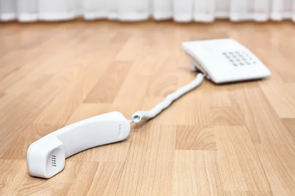 White telephone on the parquet flooring in the room. — Stock Photo, Image