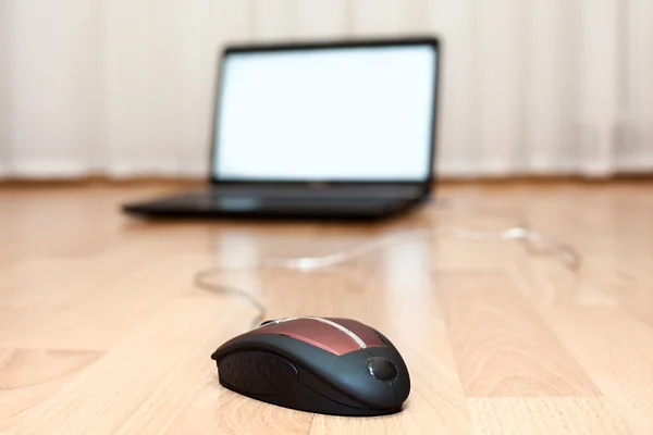 Opened laptop and a computer mouse on the floor of the room — Stock Photo, Image