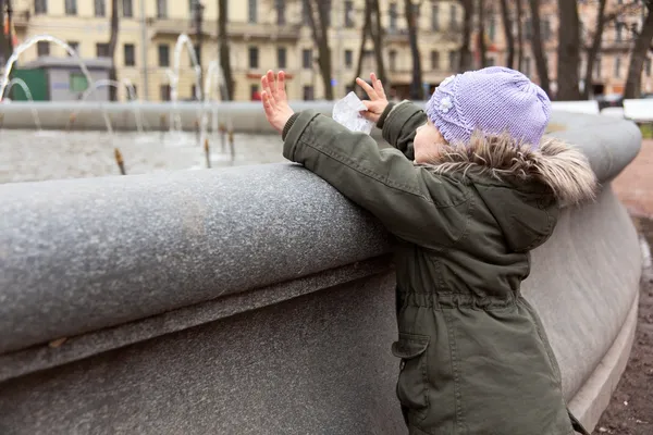 Little girl near the fountain in autumn — Stock Photo, Image