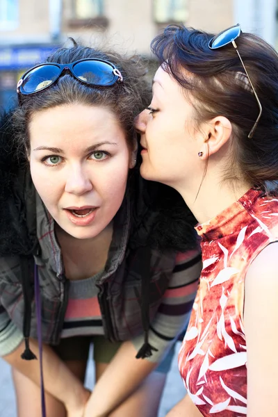 Jonge mooie vrouw fluistert iets te vriendin in haar oor — Stockfoto