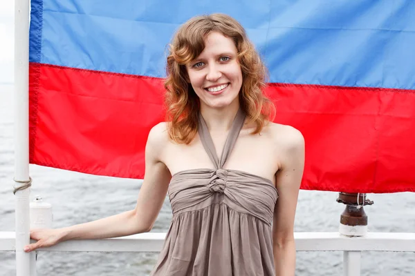 Una joven rusa hermosa de pie bajo la bandera de Rusia — Foto de Stock