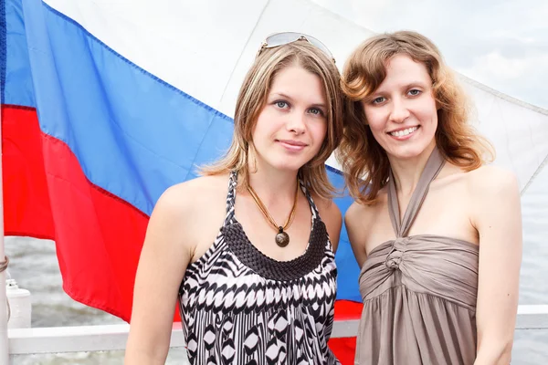 Two Russian beautiful young females are standing under flag of Russia — Stock Photo, Image