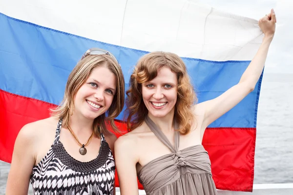 Dos hermosas mujeres rusas están de pie bajo la bandera de Rusia —  Fotos de Stock