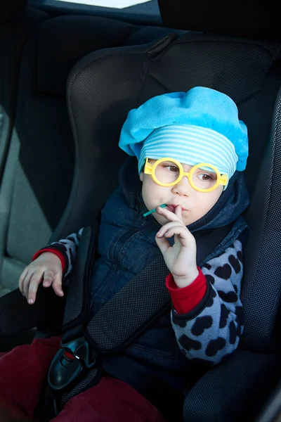 Little child sitting in carseat in vehicle with lollipop — Stock Photo, Image