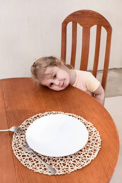 Malé dítě sedící spolu u stolu s prázdný talíř — Stock fotografie
