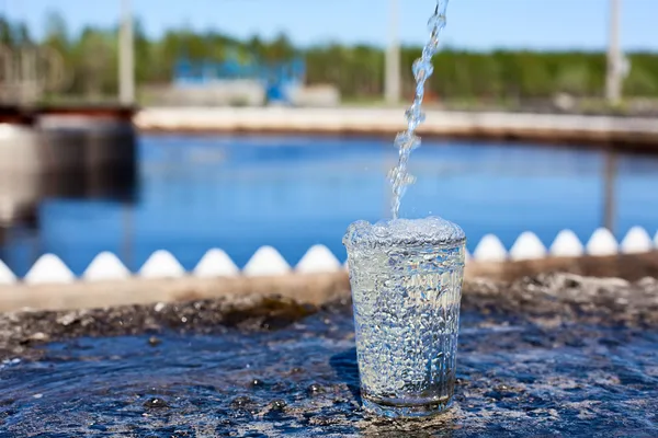 Sauberes Wasser, das in Glas gegossen wird, das auf der Wasseraufbereitungsanlage steht — Stockfoto