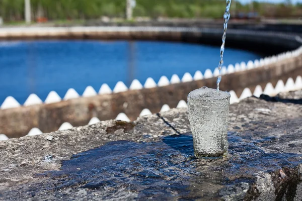 Agua limpia vertiendo en el vidrio de pie en el setler tratamiento de agua — Foto de Stock