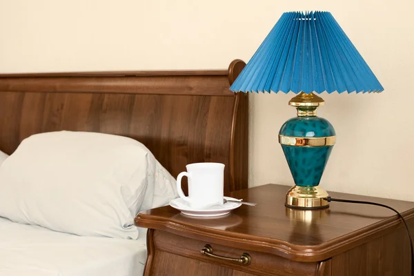 Bílý hrnek a lampu na nočním stolku — Stock fotografie