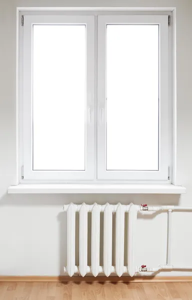 Ventana de doble puerta de plástico blanco con radiador debajo Imagen de archivo