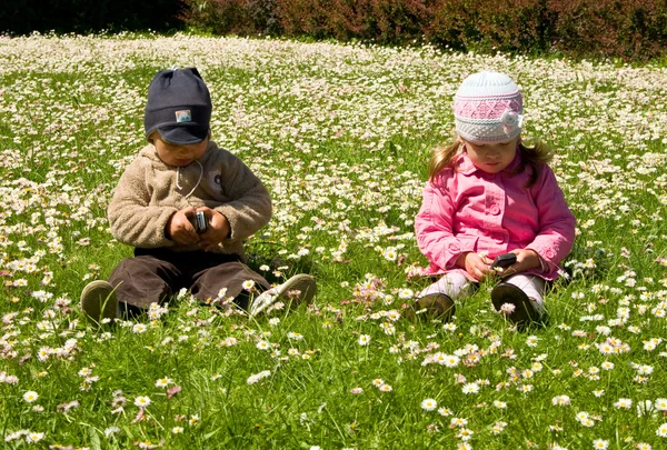 Menino e menina brincando no parque com telefones celulares — Fotografia de Stock