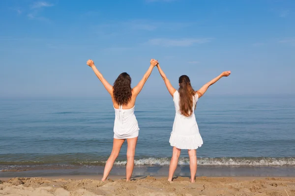 Sahil üzerinde uzanmış kolları olan iki genç kadın — Stok fotoğraf