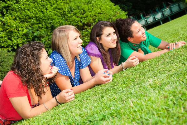 Vrouwelijke jeugdvrienden liggend op groen in het park — Stockfoto
