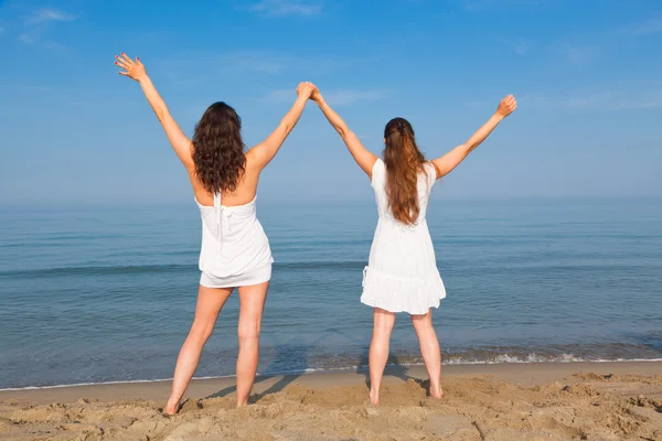해변에 뻗은 팔을 가진 두 젊은 여자 — 스톡 사진