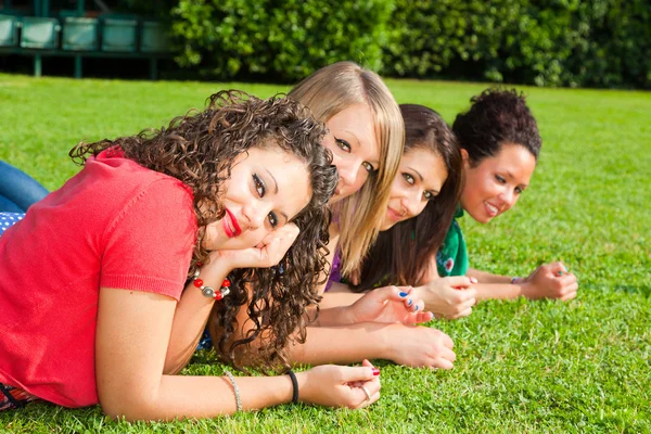 Adolescentes amigas acostadas en verde en el parque — Foto de Stock