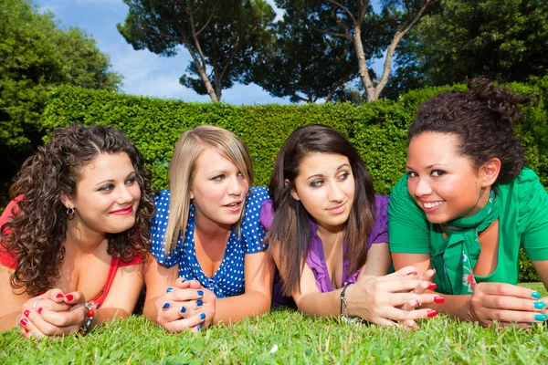 Vrouwelijke jeugdvrienden liggend op groen in het park Stockfoto