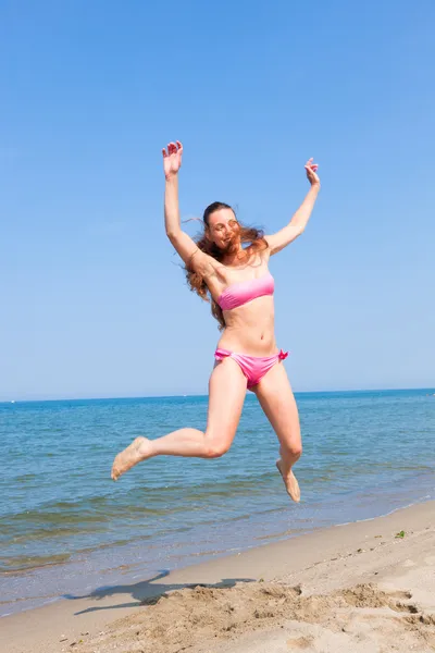 Glückliche Frau springt am Strand am Meer — Stockfoto