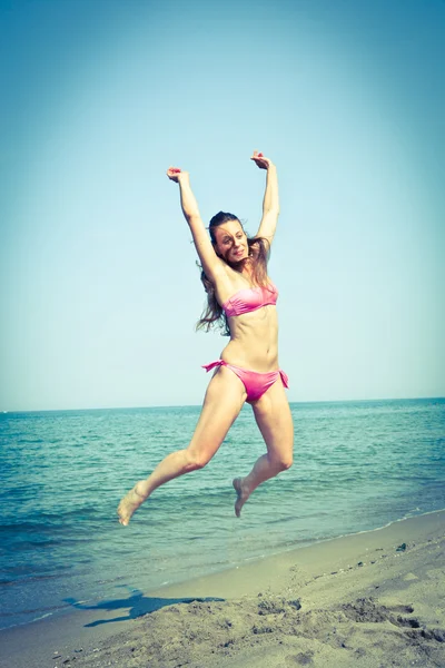 Donna felice che salta sulla spiaggia al mare — Foto Stock