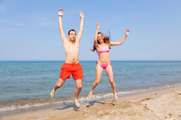 幸福的情侣在海边沙滩上跳跃 — 图库照片