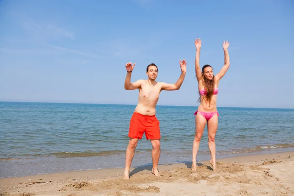 幸福的情侣在海边沙滩上跳跃 — 图库照片