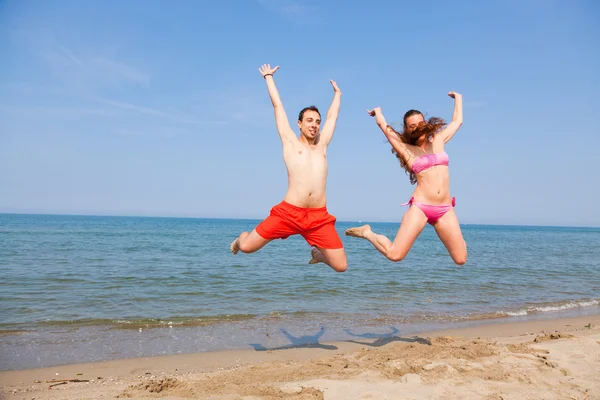Coppia felice che salta sulla spiaggia al mare — Foto Stock