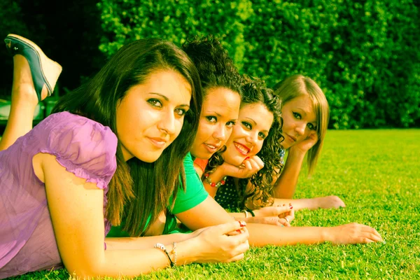 Vrouwelijke jeugdvrienden liggend op groen in het park — Stockfoto