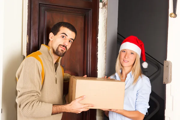 Homem recebe uma caixa de mulher jovem com chapéu de Natal — Fotografia de Stock