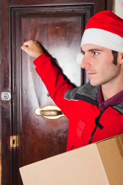 Consegna ragazzo con cappello di Natale bussare alla porta — Foto Stock