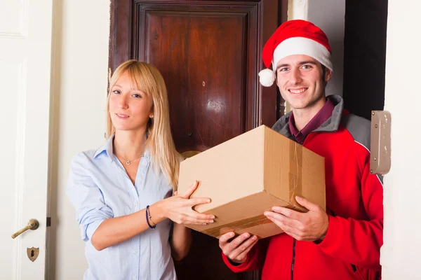 Garoto de entrega com chapéu de Natal e caixa para mulher jovem — Fotografia de Stock