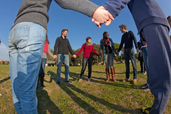 Multiracial unga hand i hand i en cirkel — Stockfoto