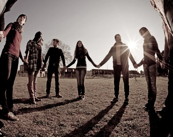 Mnohonárodnostní mladí drží za ruce v kruhu — Stock fotografie