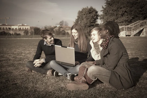 Vysokoškoláky s počítačem v parku — Stock fotografie