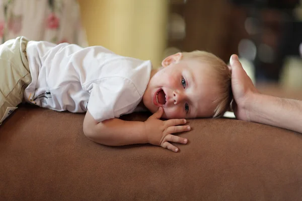 Мальчик лежит на спинке дивана — стоковое фото