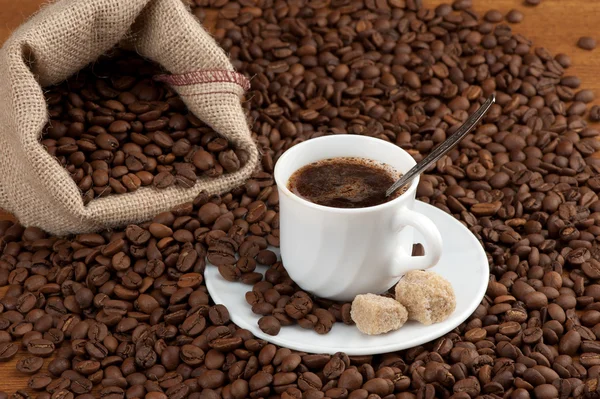 Šálek kávy s jutovým pytlem pražených bobů — Stock fotografie