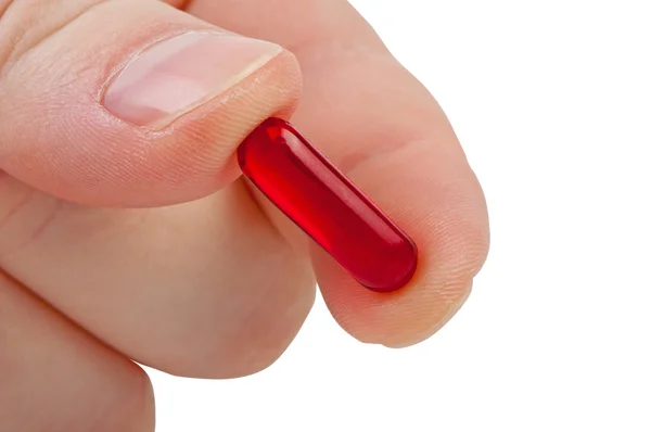 Red pill in fingers close up. — Stock Photo, Image