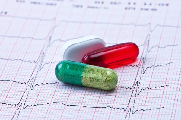 Таблетки и капсулы на кардиограмме . — стоковое фото