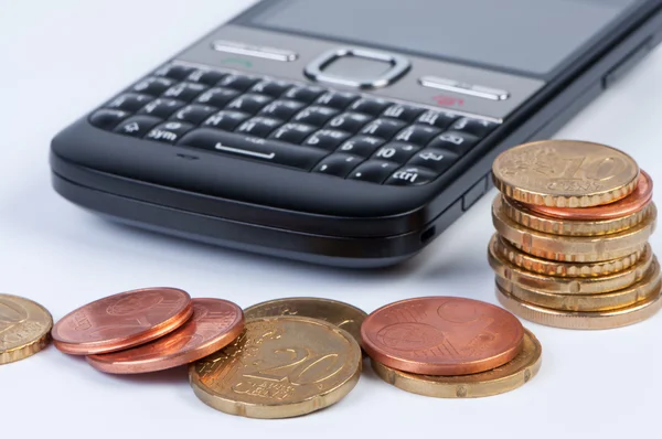 Mobile phone with coins closeup. — Stock Photo, Image