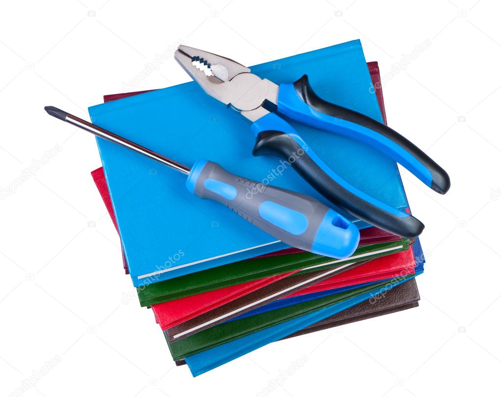 Building tool, screwdriver and pliers on a stack of books.