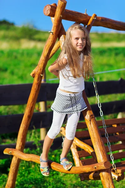 Cute little girl with blond long hair playing on wooden chain sw