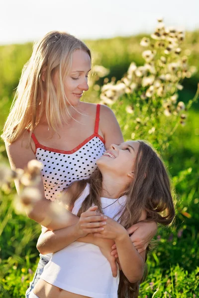 Hermosa madre y familia hija jugando en el prado al atardecer —  Fotos de Stock