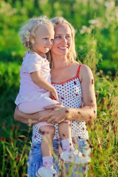 Mooie moeder met krullend hoofdige blond dochtertje op mead — Stockfoto