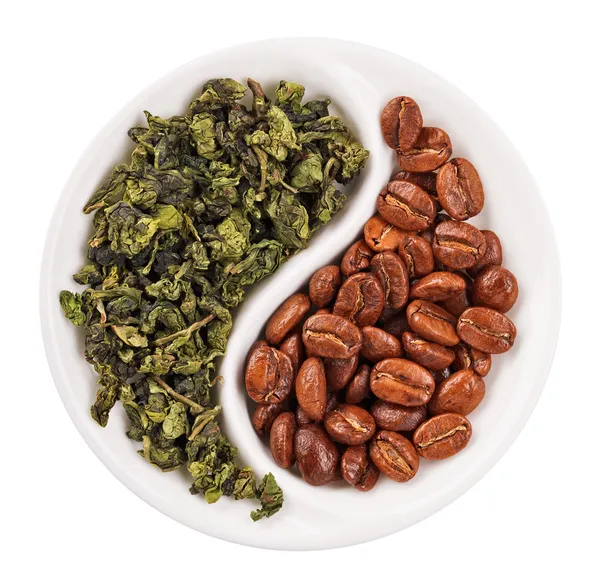 Green leaf tea versus coffee beans in Yin Yang shaped plate, iso — Stock Photo, Image