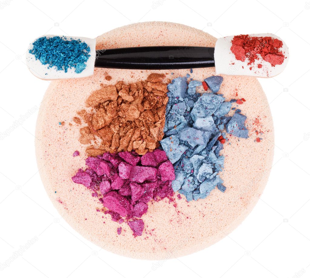Heap of broken multicolor eyeshadow over makeup sponge, isolated