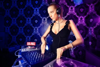 Sexy young blonde lady DJ playing music in night club clipart