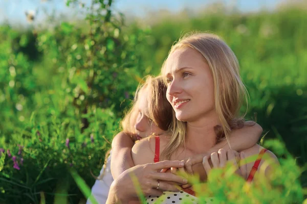 美しい母と娘の緑豊かな緑の草の牧草地の上に座って — ストック写真