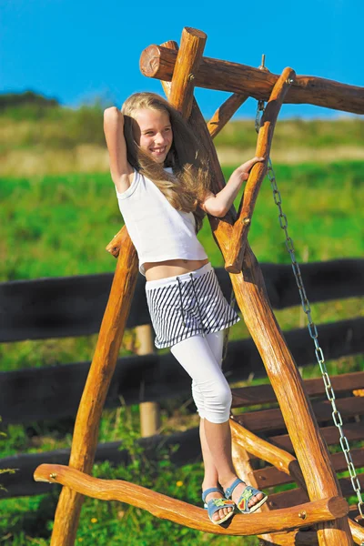 Sarı uzun saçlı ahşap zinciri sw üzerinde oynarken sevimli küçük kız — Stok fotoğraf