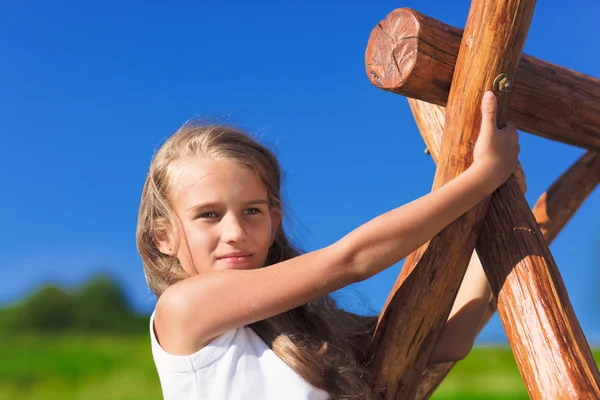 Linda niña con el pelo largo rubio jugando en la cadena de madera sw —  Fotos de Stock