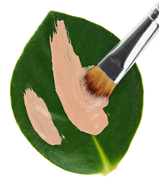 Curso de maquiagem de fundação líquida bege com escova sobre folha verde — Fotografia de Stock