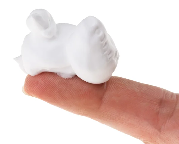 Образец пены (крема) на указательном пальце, выделенный на белом — стоковое фото